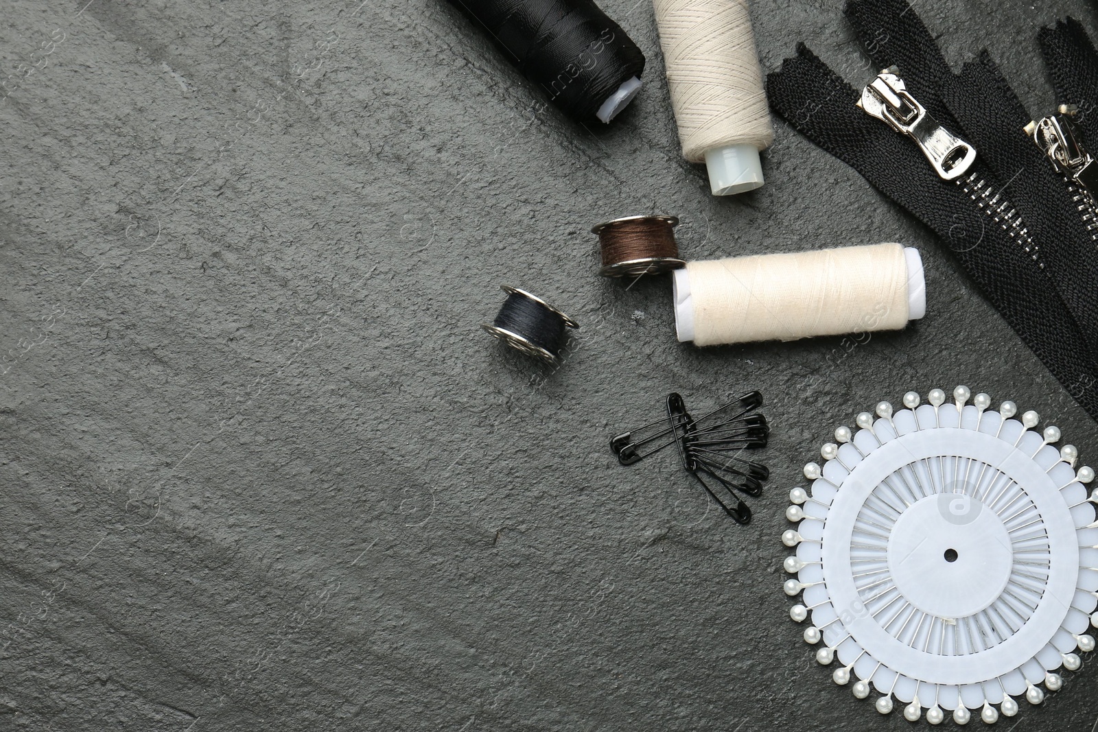 Photo of Flat lay composition with different sewing supplies on dark textured table. Space for text