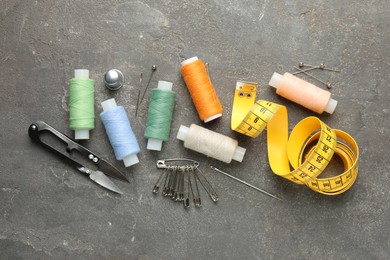 Photo of Flat lay composition with different sewing supplies on grey textured table