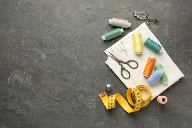 Photo of Flat lay composition with different sewing supplies on grey textured table. Space for text