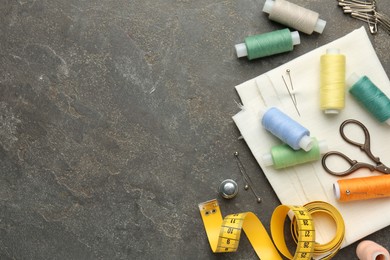 Photo of Flat lay composition with different sewing supplies on grey textured table. Space for text