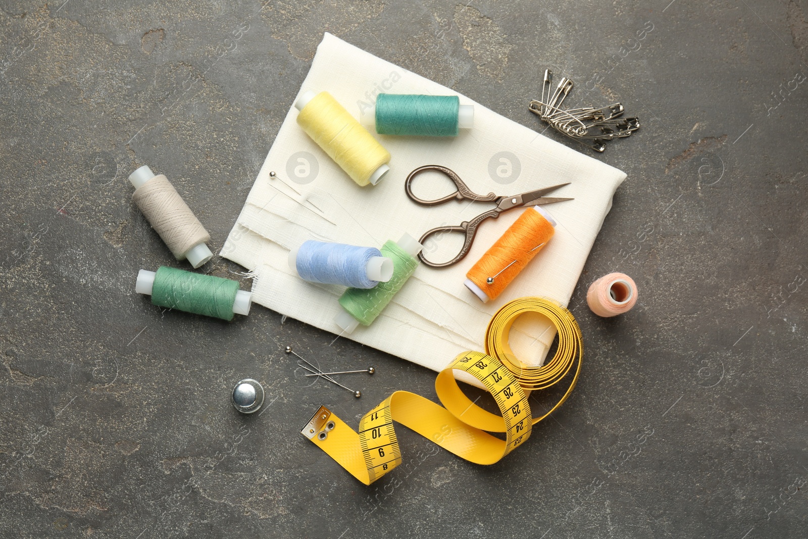 Photo of Flat lay composition with different sewing supplies on grey textured table