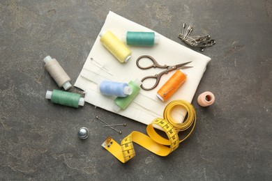 Photo of Flat lay composition with different sewing supplies on grey textured table