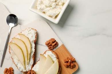 Photo of Delicious ricotta bruschettas with pear and walnut on white marble table, flat lay. Space for text