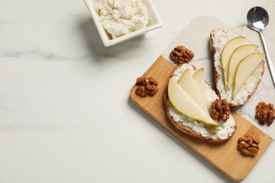 Photo of Delicious ricotta bruschettas with pear and walnut on white marble table, flat lay. Space for text