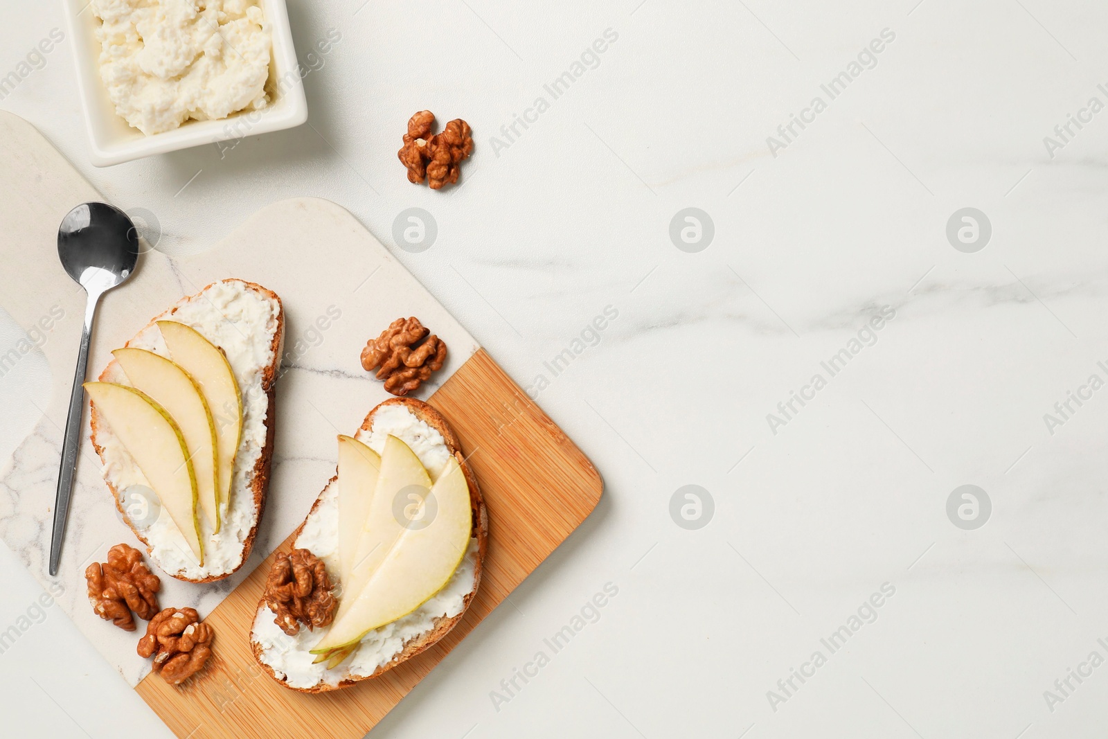 Photo of Delicious ricotta bruschettas with pear and walnut on white marble table, flat lay. Space for text