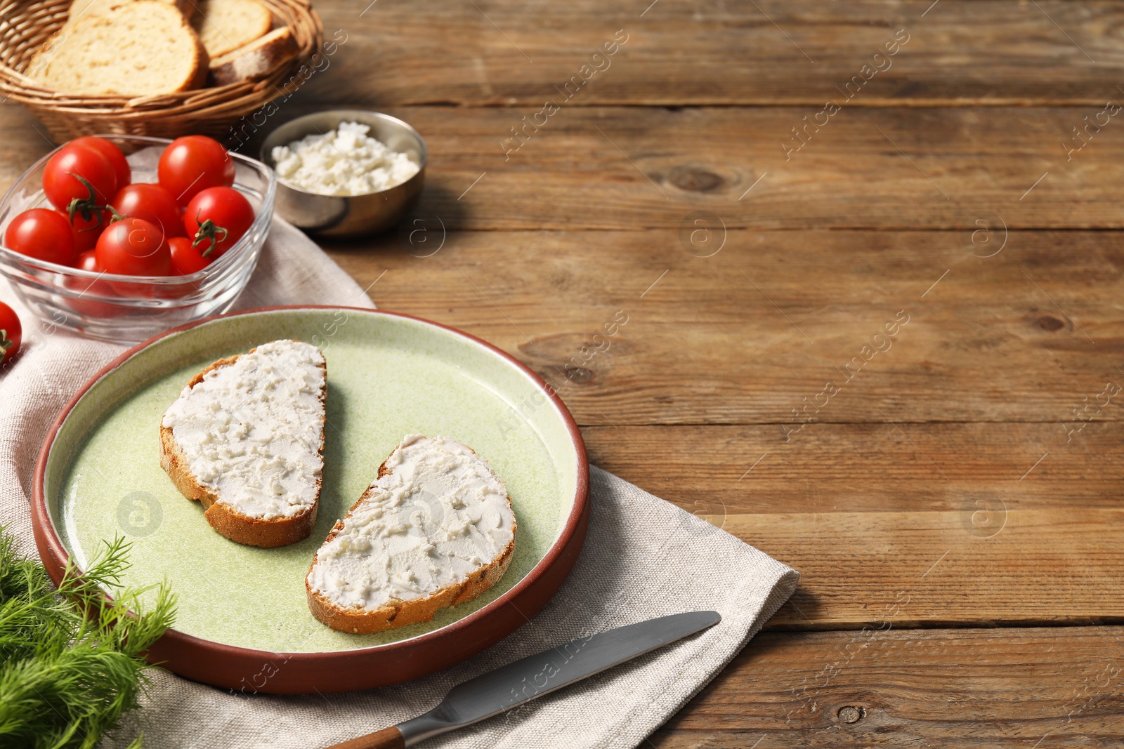 Photo of Delicious ricotta bruschettas and products on wooden table. Space for text