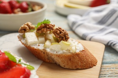 Delicious ricotta bruschetta with pear and walnut on wooden table, closeup