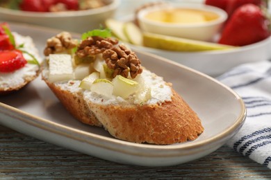 Delicious ricotta bruschetta with pear and walnut on wooden table, closeup