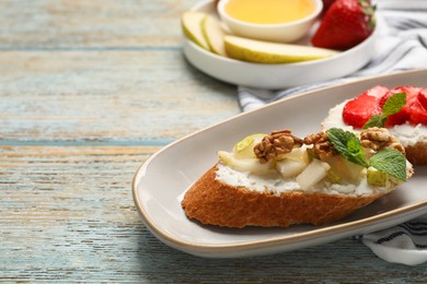 Delicious ricotta bruschettas with pear, strawberry and walnut on wooden table, closeup. Space for text