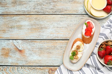 Photo of Delicious ricotta bruschettas with pear, strawberry and walnut on wooden table, top view. Space for text