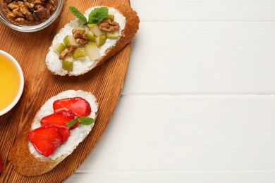 Delicious ricotta bruschettas with pear, strawberry and walnut on white wooden table, top view. Space for text