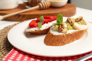 Delicious ricotta bruschettas with pear, strawberry and walnut on white table, closeup