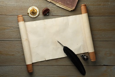 Sheet of old parchment paper, wax stamp, feather, inkwell, candle and vintage book on wooden table, top view