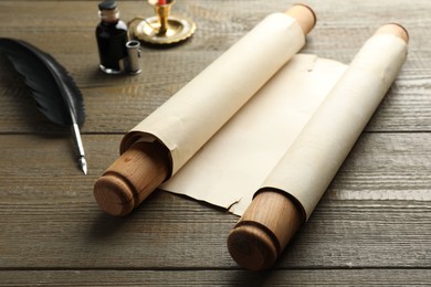 Sheet of old parchment paper with handles, black feather and inkwell on wooden table