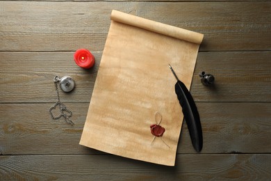 Sheet of old parchment paper with wax stamp, feather, inkwell, candle and pocket chain clock on wooden table, top view