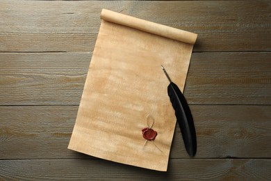 Sheet of old parchment paper with wax stamp and black feather on wooden table, top view