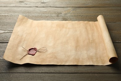 Sheet of old parchment paper with wax stamp on wooden table