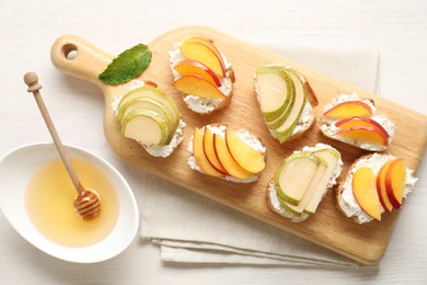 Photo of Delicious ricotta bruschettas with pears, apricots and honey on white wooden table, flat lay