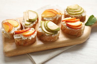 Photo of Delicious ricotta bruschettas with pears and apricots on white wooden table, closeup