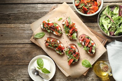 Delicious ricotta bruschettas with tomatoes, arugula and basil on wooden table, flat lay