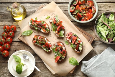 Delicious ricotta bruschettas with tomatoes, arugula and basil on wooden table, flat lay