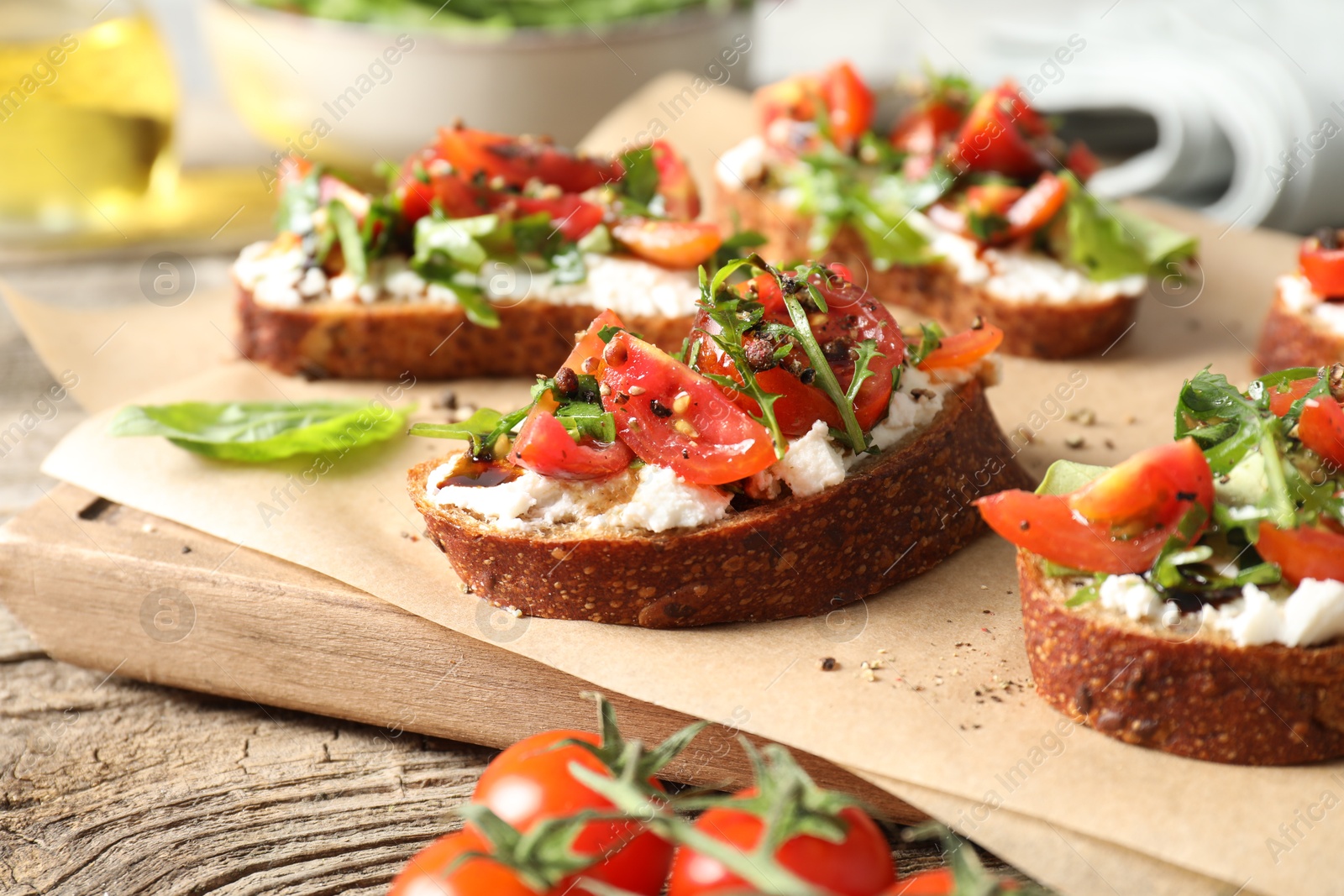 Photo of Delicious ricotta bruschettas with tomatoes and arugula on wooden table, closeup