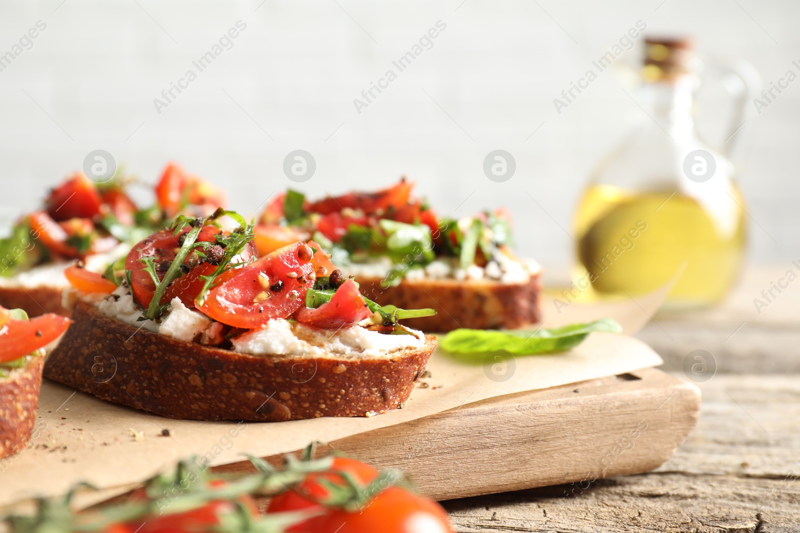 Photo of Delicious ricotta bruschettas with tomatoes and arugula on wooden table, closeup