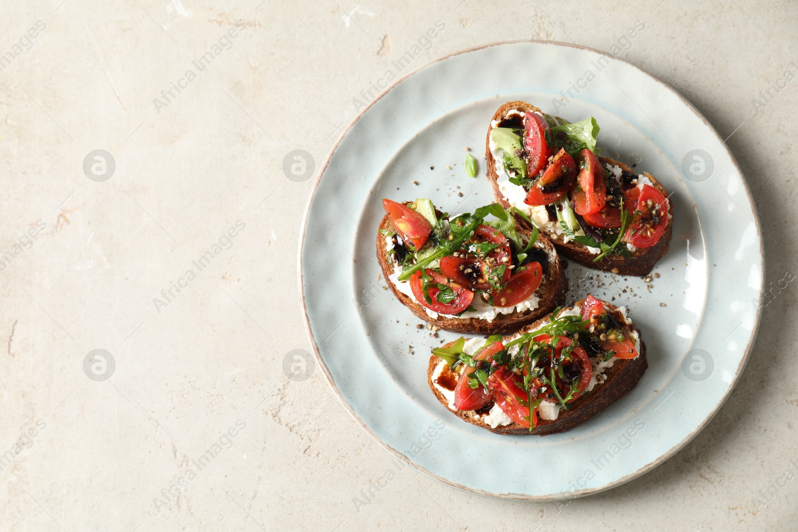 Photo of Delicious bruschettas with ricotta cheese, tomatoes and arugula on light table, top view. Space for text