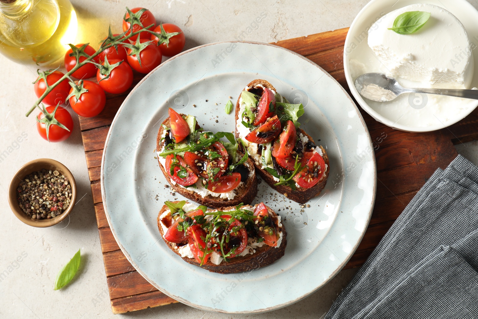 Photo of Delicious bruschettas with ricotta cheese, tomatoes, arugula and peppercorns on light table, flat lay