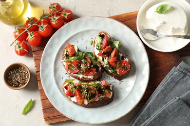 Delicious bruschettas with ricotta cheese, tomatoes, arugula and peppercorns on light table, flat lay