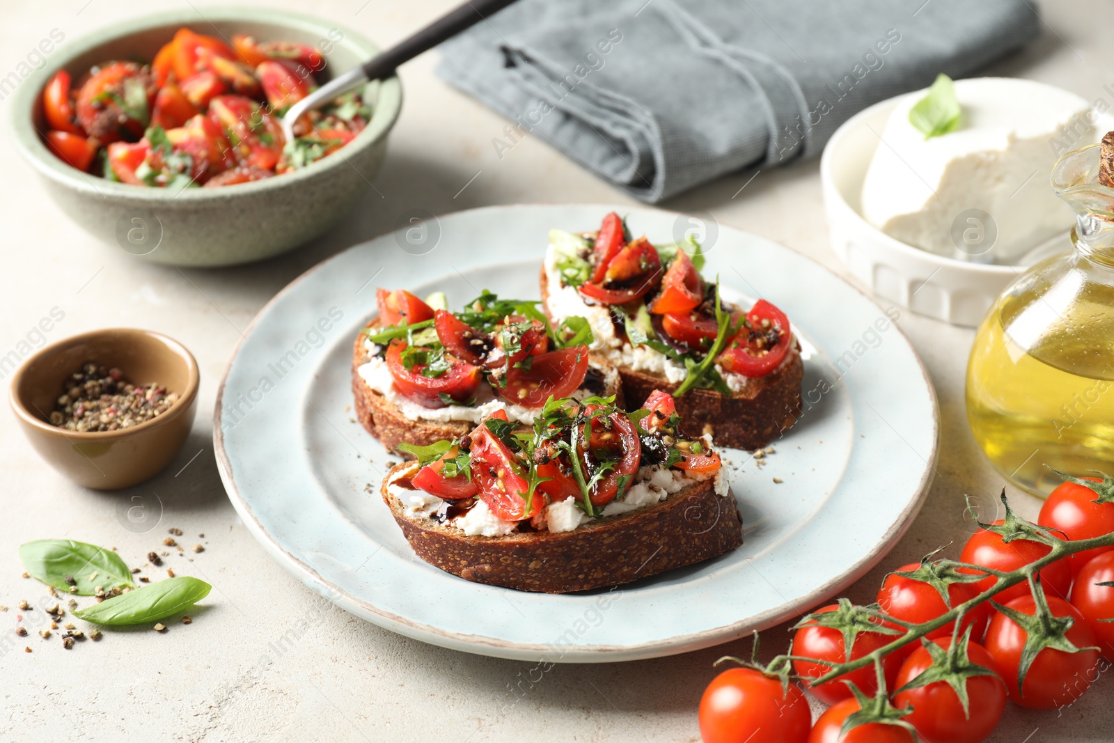 Photo of Delicious bruschettas with ricotta cheese, tomatoes, arugula and peppercorns on light table, closeup