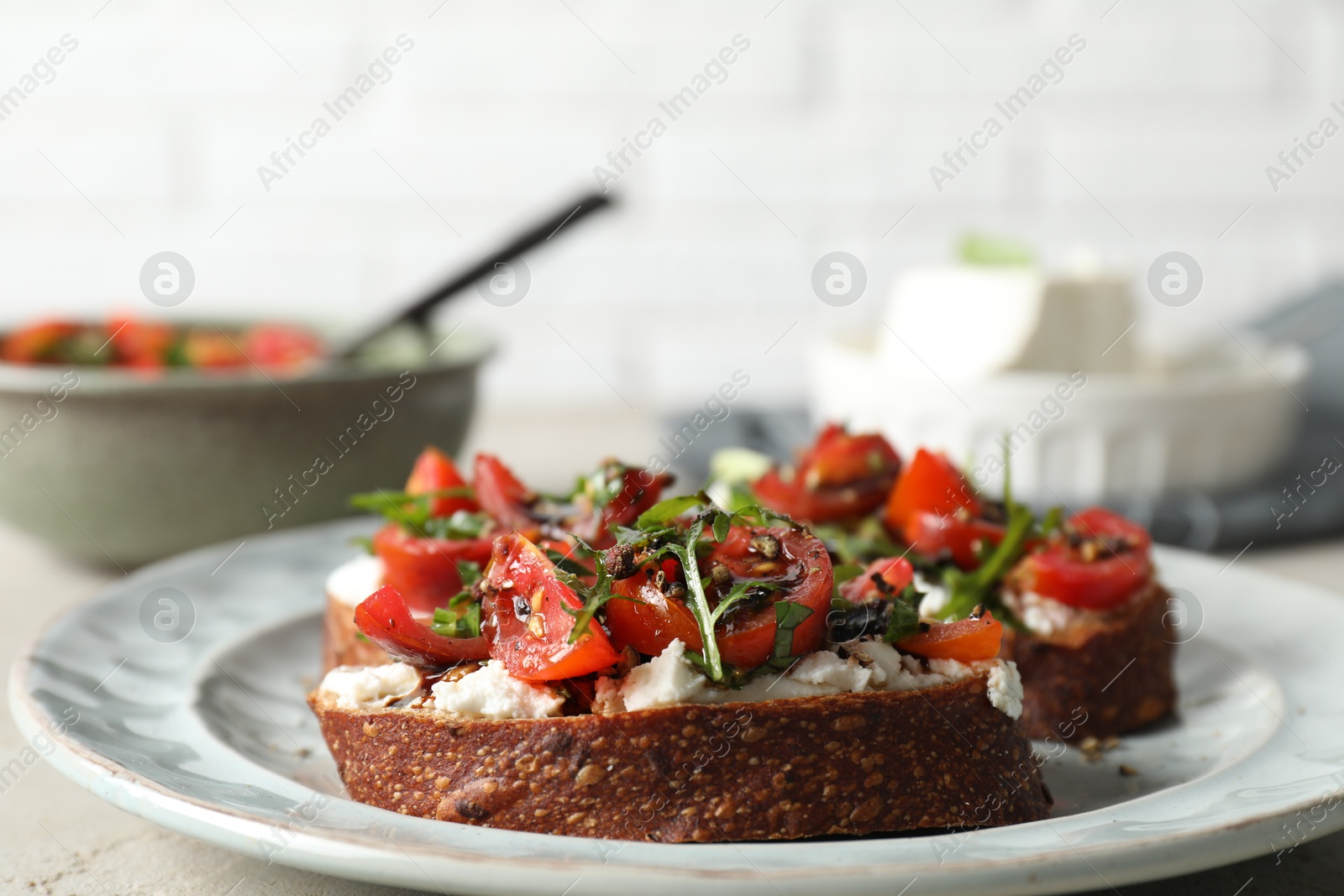 Photo of Delicious bruschettas with ricotta cheese, tomatoes, and arugula on light table, closeup