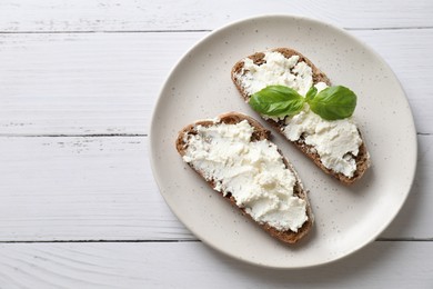 Photo of Bruschettas with ricotta cheese and basil on white wooden table, top view. Space for text