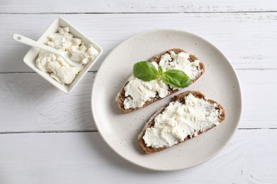 Bruschettas with ricotta cheese and basil on white wooden table, top view