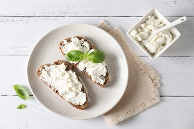 Bruschettas with ricotta cheese and basil on white wooden table, top view