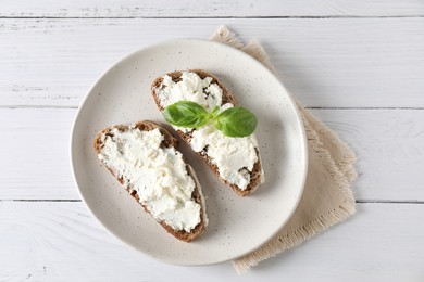 Bruschettas with ricotta cheese and basil on white wooden table, top view