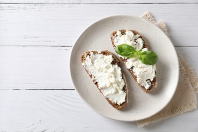 Bruschettas with ricotta cheese and basil on white wooden table, top view. Space for text