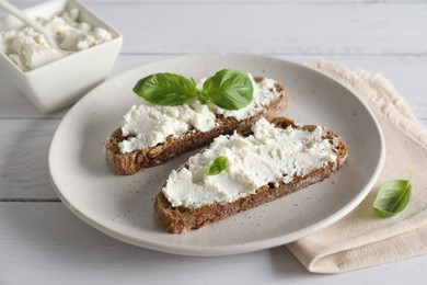 Bruschettas with ricotta cheese and basil on white wooden table, closeup