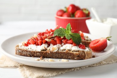 Bruschettas with ricotta cheese, chopped strawberries and mint on white wooden table, closeup