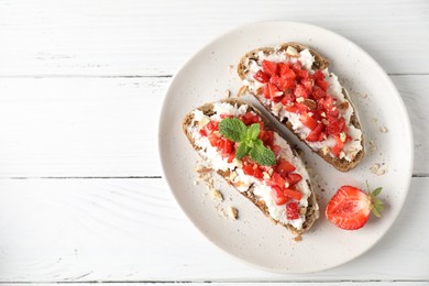 Photo of Bruschettas with ricotta cheese, chopped strawberries and mint on white wooden table, top view. Space for text