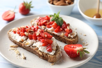 Bruschettas with ricotta cheese, chopped strawberries and mint on blue wooden table, closeup