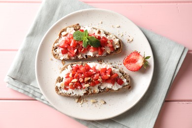 Photo of Bruschettas with ricotta cheese, chopped strawberries and mint on pink wooden table, top view