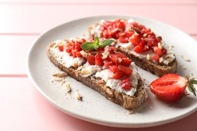 Bruschettas with ricotta cheese, chopped strawberries and mint on pink wooden table, closeup