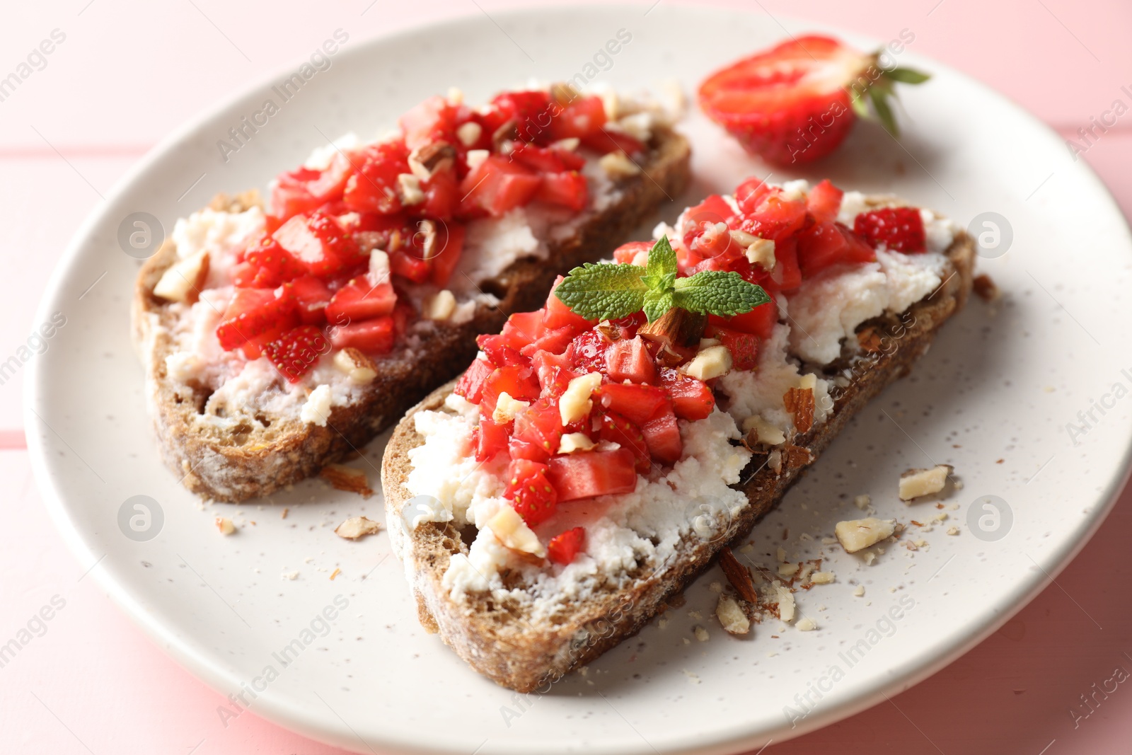 Photo of Bruschettas with ricotta cheese, chopped strawberries and mint on table, closeup