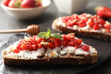 Photo of Bruschettas with ricotta cheese, chopped strawberries and mint on table, closeup