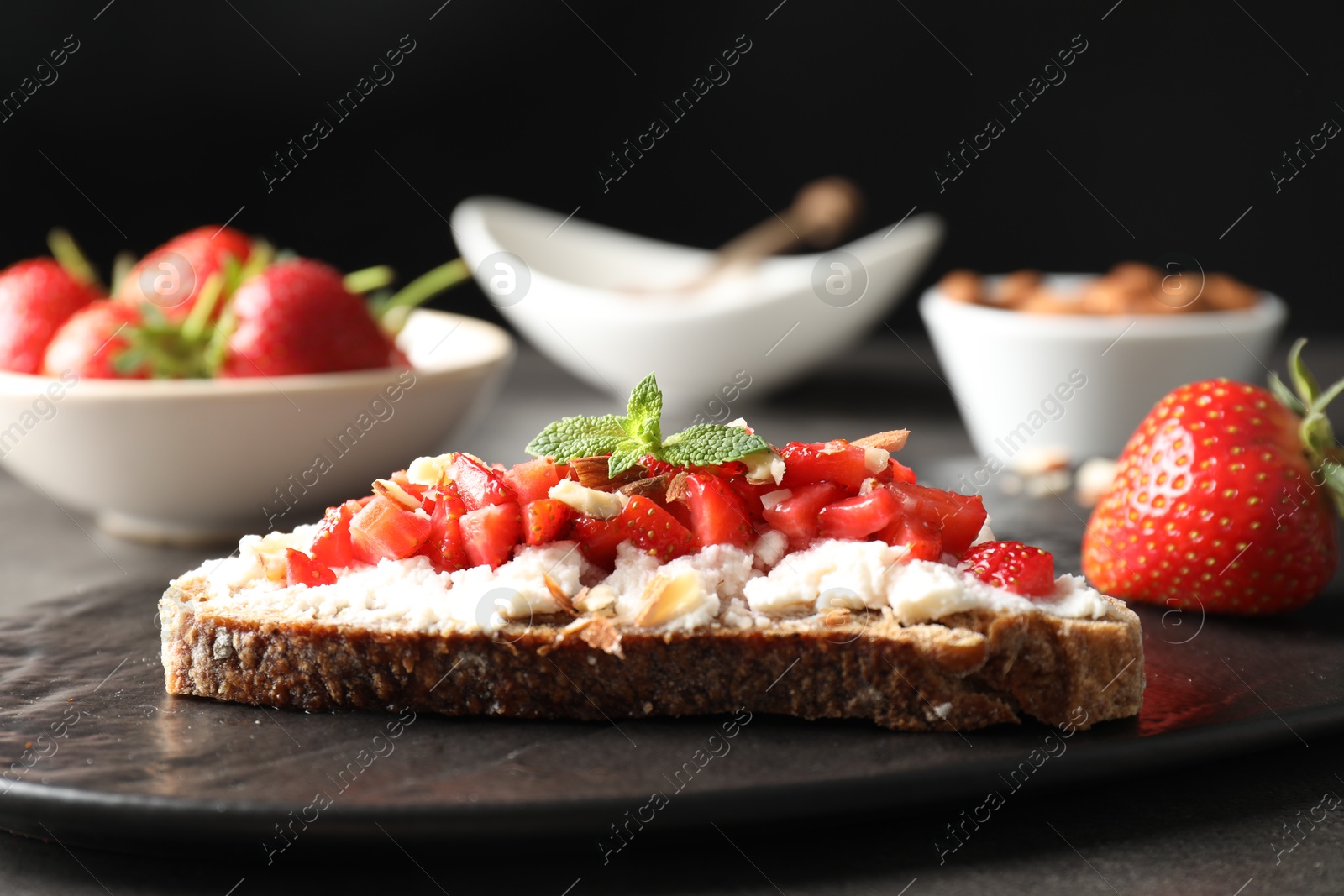 Photo of Bruschetta with ricotta cheese, chopped strawberries and mint on table, closeup