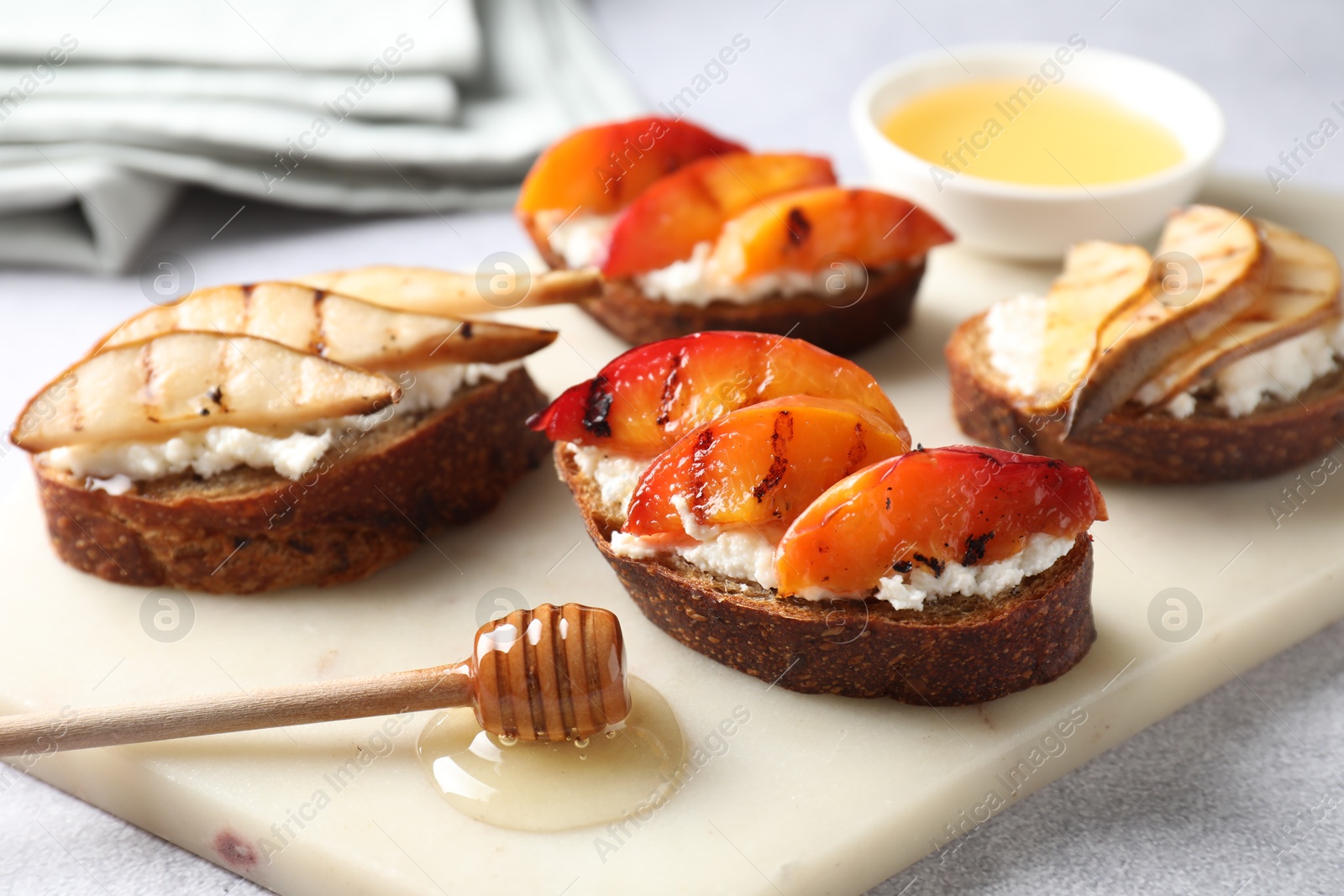 Photo of Delicious bruschettas with ricotta cheese and honey on light grey table, closeup