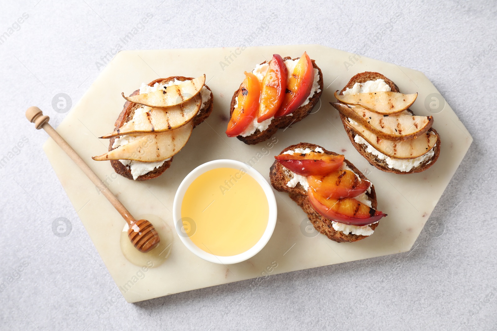 Photo of Delicious bruschettas with ricotta cheese and honey on light grey table, top view