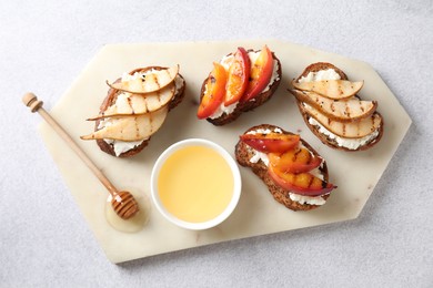 Delicious bruschettas with ricotta cheese and honey on light grey table, top view