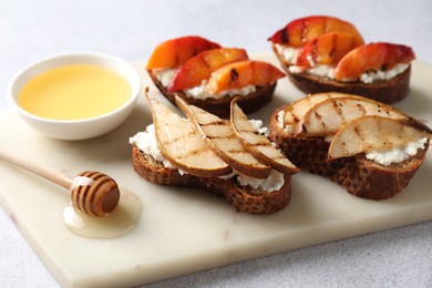 Photo of Delicious bruschettas with ricotta cheese and honey on light grey table, closeup